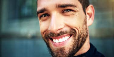 looking at the camera, a man's inner joy is conveyed by his smile