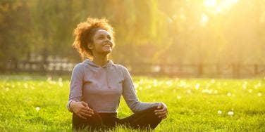 smiling woman sitting on the grass and looking up