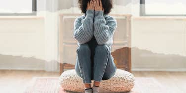Unhappy woman sitting on pouf in living room