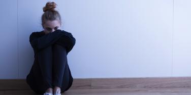 woman hugging chest against wall