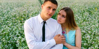 woman hugs her man from behind standing on the field