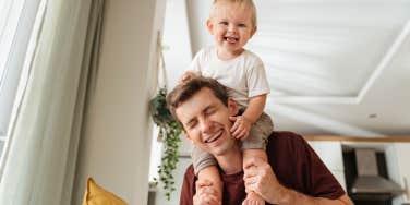 Laughing father giving his kid piggyback ride on shoulders