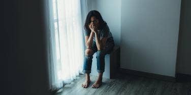 woman sitting in corner with head in hands