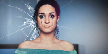 crying woman in front of broken glass