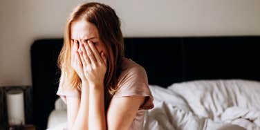 woman grieving, hands over face in bed