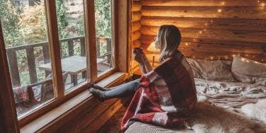 woman wrapped in blanket looking out the window