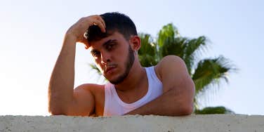 guy in white tank top with hand on head