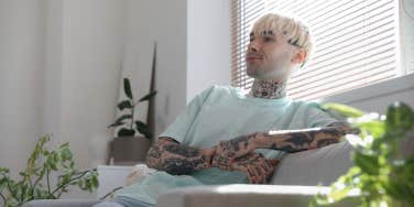 man with tattoos sitting on couch