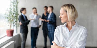 woman worries while male coworkers talk behind her back