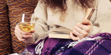 woman having a glass of wine and reading