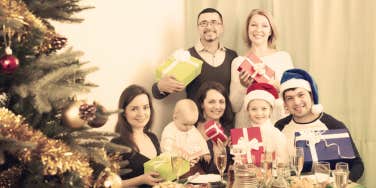 family perfectly posed by Christmas tree with gifts
