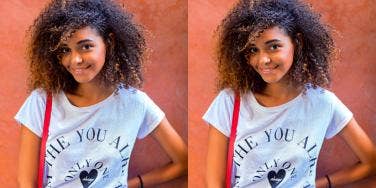 young Black woman smiles at the camera on an orange background