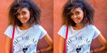 young Black woman smiles at the camera on an orange background