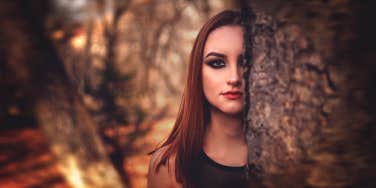 woman standing behind a tree