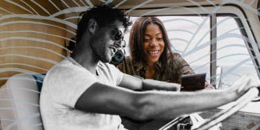 Man behind the wheel of a car, girl flirting showing him a photo