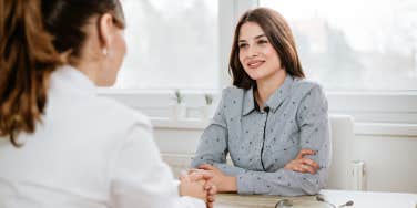 young woman talking to a doctor across a desk in an office