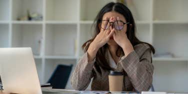 Frustrated employee holds her head in front of computer.
