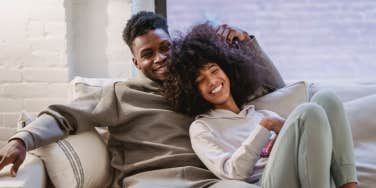 Couple cuddling and smiling on couch