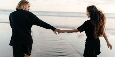 guy and girl holding hands walking on the beach