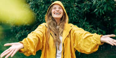 woman smiling in the rain in a yellow raincoat