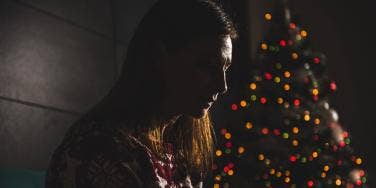 grieving woman in the darkness with Christmas tree