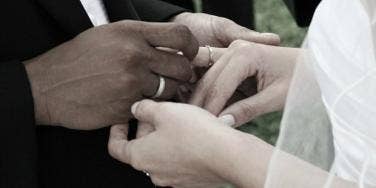 groom putting bride's wedding ring on