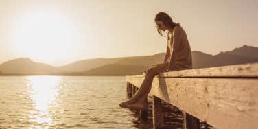 woman sitting on pier by water