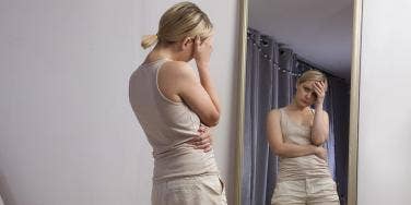 woman looking at mirror unhappily