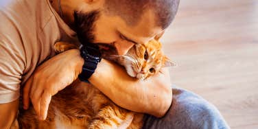 man cuddling with cat