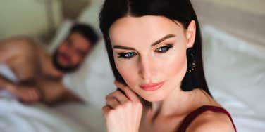 woman thinking in bed with cheating boyfriend next to her