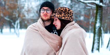 couple cuddling under blanket in the snow