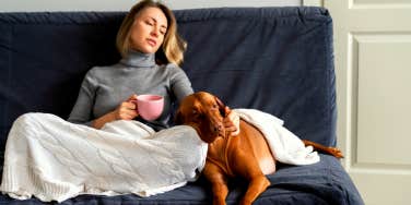 sad woman sitting on the couch with her dog