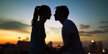 man and woman in shadow against sunset about to kiss