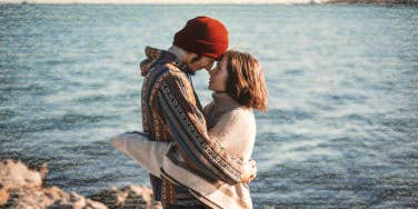 Couple foreheads together with the water behind them 