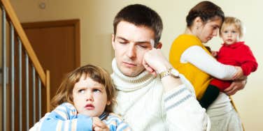 Couple with small children in a quarrel the silence and distance between them enhances the tension