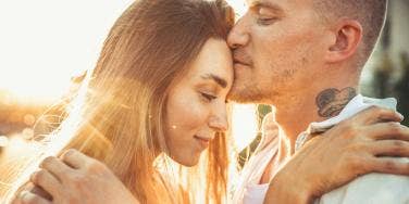 man kissing woman's forehead