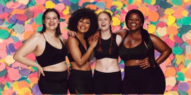 4 women feeling confident about their bodies standing in front of a colorful background