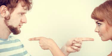 A couple stare at each other and point the finger at one another