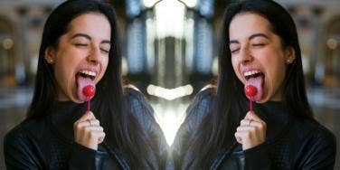 woman with tongue out licking lollipop