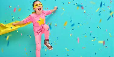 child in mask having fun in front of confetti