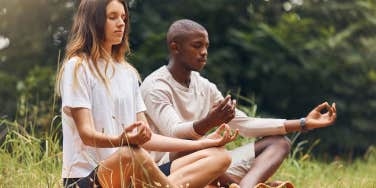 couple meditating together in grass