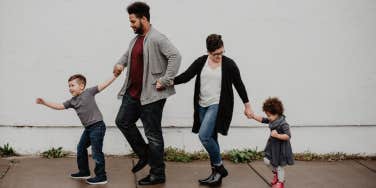 family holding hands on sidewalk
