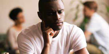 frustrated man sits alone in room of people