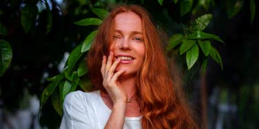 woman smiling posing in front of greenery