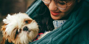 Woman holding her Shih Tzu crying 