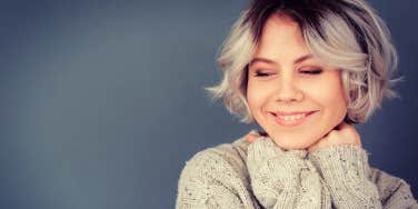 young woman smiling peacefully on a grey background