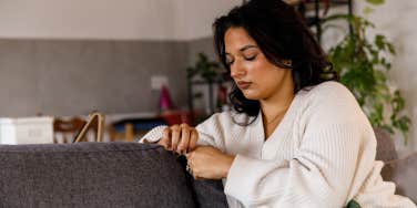 Sad woman playing with her hands on the couch 