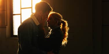 man and woman hugging with sunlight behind them through window