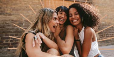 three young women laughing together outdoors 