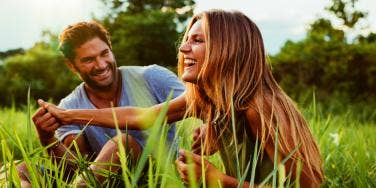 man and woman smiling in grass